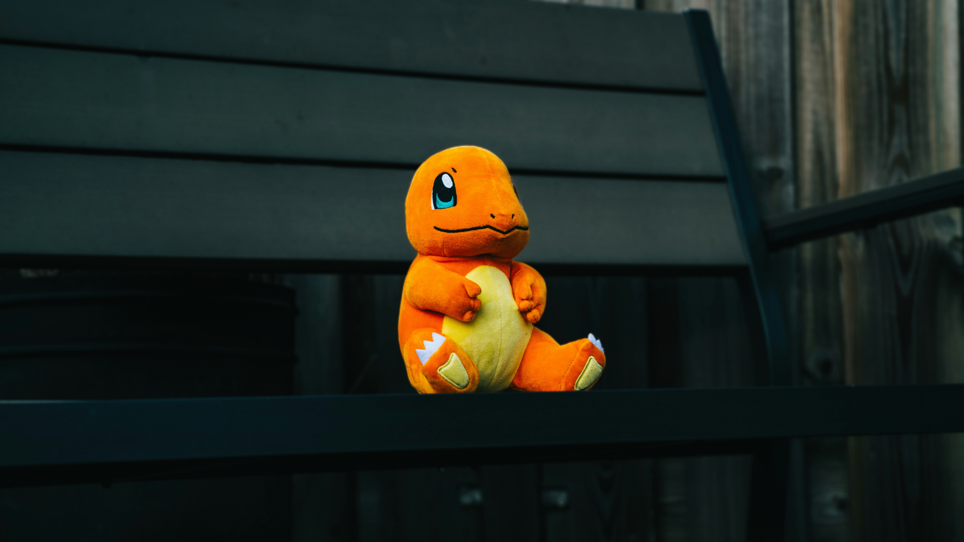 A plush toy of Charmander, one of the most iconic Pokémon, sitting on a dark wooden bench. Symbolizing digital collectibles, AR gamification, and the psychology of collection that makes Pokémon Go such an addictive digital experience.